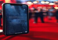 A photorealistic image of a smartphone screen showing a social media post with a cryptic message, surrounded by blurred background of a red carpet event with celebrities.