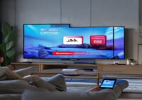 A photorealistic image of a modern living room with a large TV screen displaying a YouTube ad that shows a product with a 'Shop Now' button overlay. A person is using a smartphone, and the scene conve