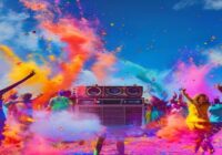 A vibrant Holi festival scene with people throwing colorful powders in the air, dancing to music under a bright blue sky. In the background, a DJ booth with speakers. Photorealistic, high detail, fest