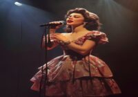 Photorealistic image of Imelda May performing on stage with a microphone, wearing a vintage dress, dramatic lighting, no text or logos